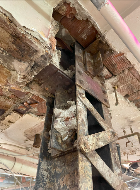 Close-up of existing structural steel connection and surrounding masonry/ceiling conditions during renovation.